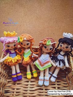 four crocheted dolls sitting in a wicker basket