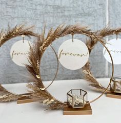 three ornaments with the word forever written on them and some dried grass in front of them