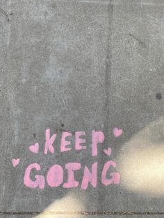 graffiti written on the sidewalk says keep going and pink hearts are painted on it's side