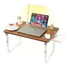 a laptop computer sitting on top of a wooden desk next to a cup of coffee