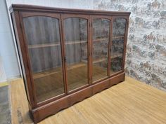 an old china cabinet with glass doors on the front and bottom shelves, sitting on a wooden floor