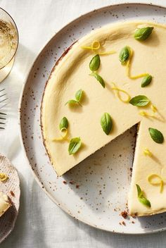 a cheesecake on a white plate next to a glass of wine and utensils