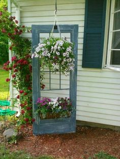 an old window is filled with flowers and hanging from it's frame, as well as a potted planter