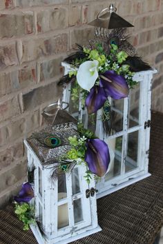 two white windows with purple and green flowers on them sitting next to a brick wall