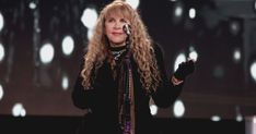 a woman with long curly hair holding a microphone