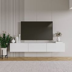 a flat screen tv sitting on top of a white entertainment center next to a potted plant