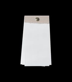 a white piece of paper with a button on it's end, against a black background