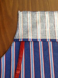 an apron with red, white and blue stripes is on the wooden table next to scissors