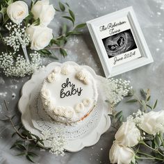 a white cake sitting on top of a table next to flowers and a framed photo