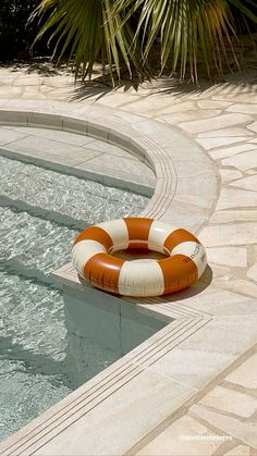 an orange and white life preserver sitting on the edge of a pool