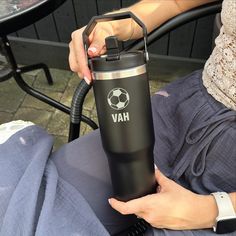 a woman holding a black and silver water bottle with the word hav on it