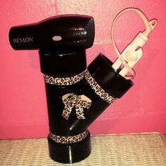 a hair dryer with leopard print on it is sitting next to a pink wall