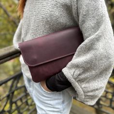 a woman is holding a long leather purse