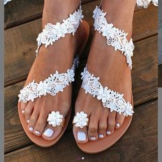 a woman wearing sandals with white lace and flowers on the toes is standing on a wooden floor