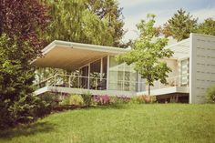 a white house sitting in the middle of a lush green field with trees and bushes