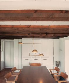 a large wooden table sitting in the middle of a room with white walls and wood beams