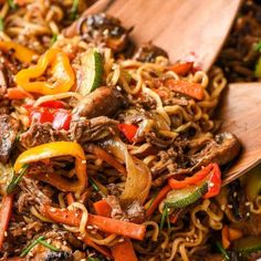 stir fry with beef and vegetables in a wooden spoon on top of a white plate