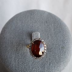 Gemporia Hessonite (Red) Garnet Ring. 8.42ctw Oval (14x10), Basket Setting. 20 Round White Topaz Stones In A Halo Around Garnet. Ring Is Yellow Gold Over 925 Silver, Weighs 4.3g. Size 6. This Is A Stunner! Exquisite Oval Gemstones With Accents, Classic Oval Gemstones With Halo Setting, Elegant Oval Cabochon Wedding Gemstones, Formal Ruby Ring With Gemstone Accents, Exquisite Oval Gemstones With Halo Setting, Exquisite Oval Gemstones For Formal Occasions, Exquisite Oval Gemstones For Formal Events, Oval Gemstones With Halo Setting For Formal Occasions, Oval Center Stone Gemstones For Formal Occasions