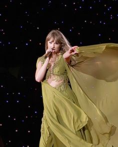 a woman in a green dress is performing on stage