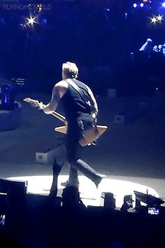 a man standing on top of a stage holding a guitar