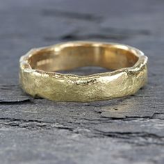 a close up of a gold wedding ring on a wooden surface with cracks in it