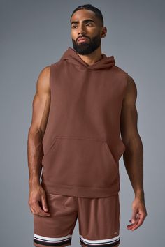 Stay cozy without sacrificing style in the Renown Sleeveless Hoodie. It has deep armholes, a kangaroo pocket, and a laid-back cut. And wait till you feel the Alo signature Renown fabric—it's smooth on the outside, a little fleecy on the side, and heavyweight for a just-right drape. Add shorts and you’re covered from the gym to the street. Athleisure Tops With Kangaroo Pocket For Streetwear, Brown Sleeveless Activewear For Sports, Sleeveless Cotton Hoodie For Loungewear, Athleisure Hoodie Top With Pockets, Casual Brown Stretch Vest, Sporty Brown Hoodie With Pockets, Alo Yoga Hooded Top With Drawstring Hood, Brown Sleeveless Activewear For Workout, Brown Sleeveless Athleisure Activewear