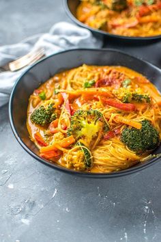 two bowls filled with pasta and broccoli on top of a gray countertop