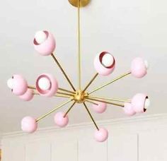 a pink and gold chandelier hangs from the ceiling in a room with white walls