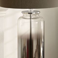 a lamp that is on top of a table next to a glass container with a red liquid in it