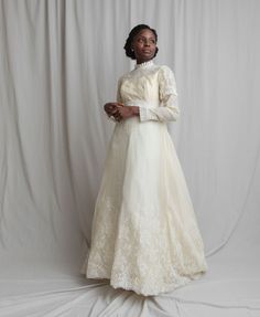 a woman in a white dress is standing on a white background with her arms crossed