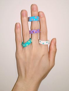 a person's hand with three different colored rings on their fingers and one is wearing a polka dot ring