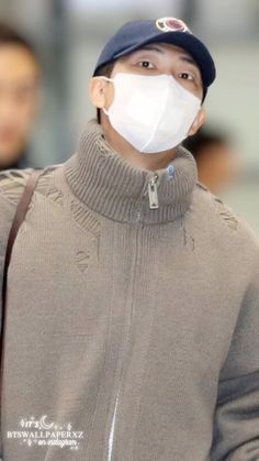 a man wearing a face mask while standing in an airport