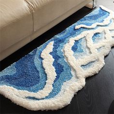 a blue and white rug sitting on top of a wooden floor next to a couch