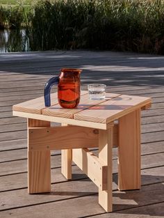 a wooden table with a pitcher on top of it next to a cup and glass