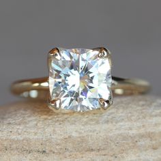 an engagement ring with a cushion cut diamond in the center on top of a rock