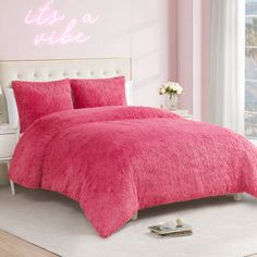 a bed with pink comforter and pillows next to a white dresser in a bedroom