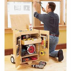 a man is working on a cabinet with tools and other items in the drawer below