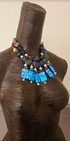 I created this one-off, bespoke beaded statement necklace from a recent sorting of my de-stash. This bold and chunky, colorful necklace contains the following components: blue crazy lace agate, rose encased lampwork beads, rhinestone balls, recycled blue-green African glass beads, emerals, sapphire, chevton amethyst, faceted crystals, jade, agate, purple freeform howlite nuggets and rhinestone rondelles. Adjusts from 15-18" and I can add additional links if requested. Closes with silver tone har Artisan Blue Beaded Necklaces, Blue Large Beads Necklace, Handmade Bold Blue Jewelry, Bold Handmade Blue Jewelry, Blue Beaded Dangle Necklaces With Natural Stones, Blue Beaded Necklaces With Natural Stones, Blue Beaded Necklaces With Natural Stones And Dangle Shape, Blue Large Beads Dangle Necklace, Blue Large Beaded Dangle Necklaces