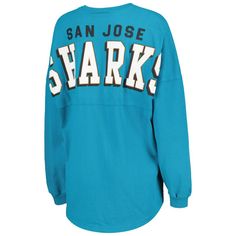 Boost your collection of official San Jose Sharks gear with this Spirit jersey T-shirt from Fanatics Branded. It features a lace-up V-neckline and dropped shoulders, ensuring that you'll be the most stylish fan on game day. The low-puff graphics on this cotton tee make it clear that your loyalty to the San Jose Sharks is second to none.Boost your collection of official San Jose Sharks gear with this Spirit jersey T-shirt from Fanatics Branded. It features a lace-up V-neckline and dropped shoulde Collegiate V-neck Top With Letter Print, Game Day Long Sleeve Tops With Team Logo, Collegiate Sports V-neck Top, Collegiate V-neck Sports Top, Long Sleeve Tops With Team Logo For Fan Gear, Fan Apparel Long Sleeve Tops With Team Logo, Long Sleeve Tops With Team Logo For Fans, Long Sleeve Tops With Team Logo, Blue Tops With Team Logo For Game Day