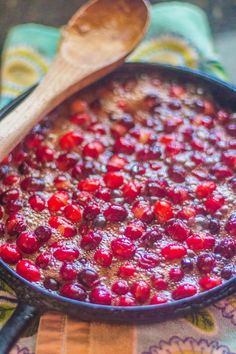 cranberry sauce in a skillet with a wooden spoon next to it on a table