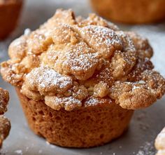 a muffin with powdered sugar on top is sitting in front of other muffins