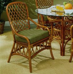 a glass topped table with two chairs and a bowl of fruit on the table next to it