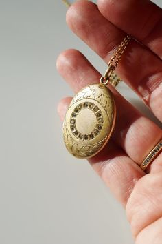 "c. 1890 large oval shape gold-fill photo locket with central \"eye\" ring of rhinestones, and border of hand engraved leafy foliage. the reverse engraved with decorative initials \"MAR\". opens to reveal two compartments for storing photos or mementos, one side with original removable frame pieces. chunky original bail. paired with a vintage gold tone 18\" chain. hallmarked for The Fineberg Manufacturing Company of Attleboro. locket 1 3/8\" lg. 1\" wd. very good/ excellent condition. some patin Luxury Antique Locket Necklace For Formal Events, Luxury Antique Gold Locket Necklace, Antique Oval Pendant Jewelry With 17 Jewels, Vintage Oval Necklaces With Rose Cut Diamonds, Victorian Yellow Gold Oval Cabochon Jewelry, Vintage Oval Necklace With Rose Cut Diamonds, Victorian Jewelry With Rose Cut Diamonds In Oval Shape, Victorian Yellow Gold Oval Jewelry, Victorian Oval Yellow Gold Jewelry