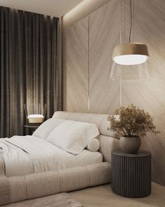 a white bed sitting next to a lamp on top of a table