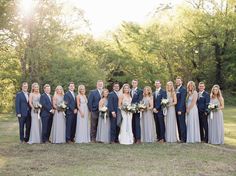 a large group of people in formal wear posing for a photo with trees in the background