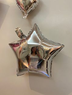 two silver star shaped foil balloons sitting on top of a white table next to each other