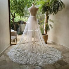 a white wedding dress on display in front of a window with trees and bushes behind it