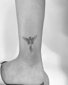 a small tattoo on the ankle of a woman with a bird flying over her head