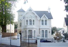 a large white house sitting on the side of a road next to a fence and trees