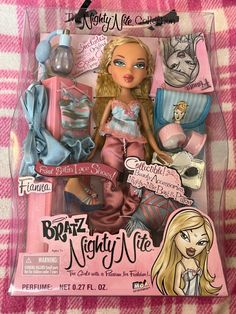 the doll is in its packaging on a pink and white checkered blanket